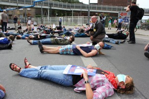 Die Teilnehmer/innen des Flashmobs legen sich auf der geplanten A100-Trasse quer